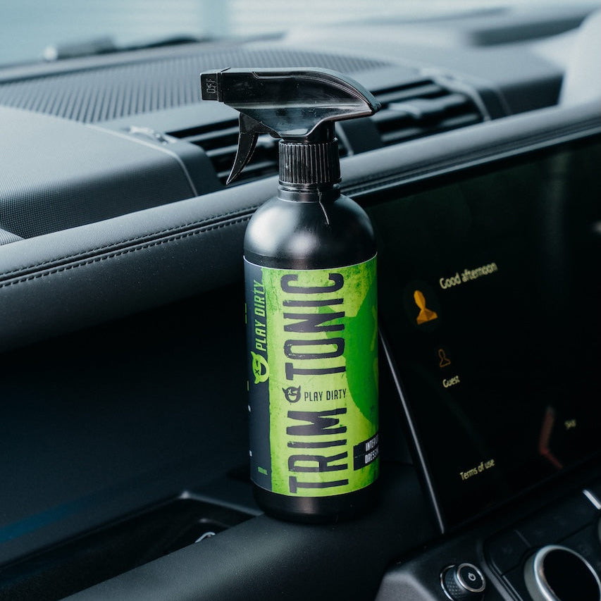 Spray bottle labeled 'Trim Tonic' on a car dashboard