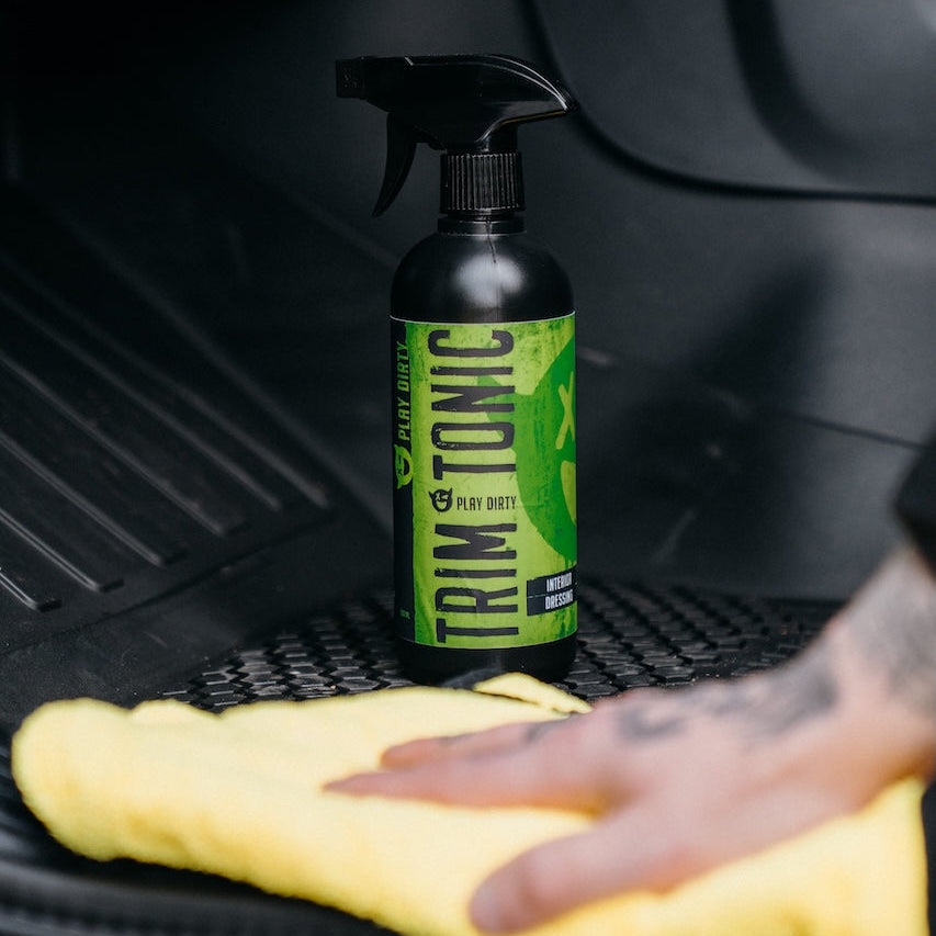 Bottle of Trim Tonic car cleaning product on a car seat with a yellow towel.